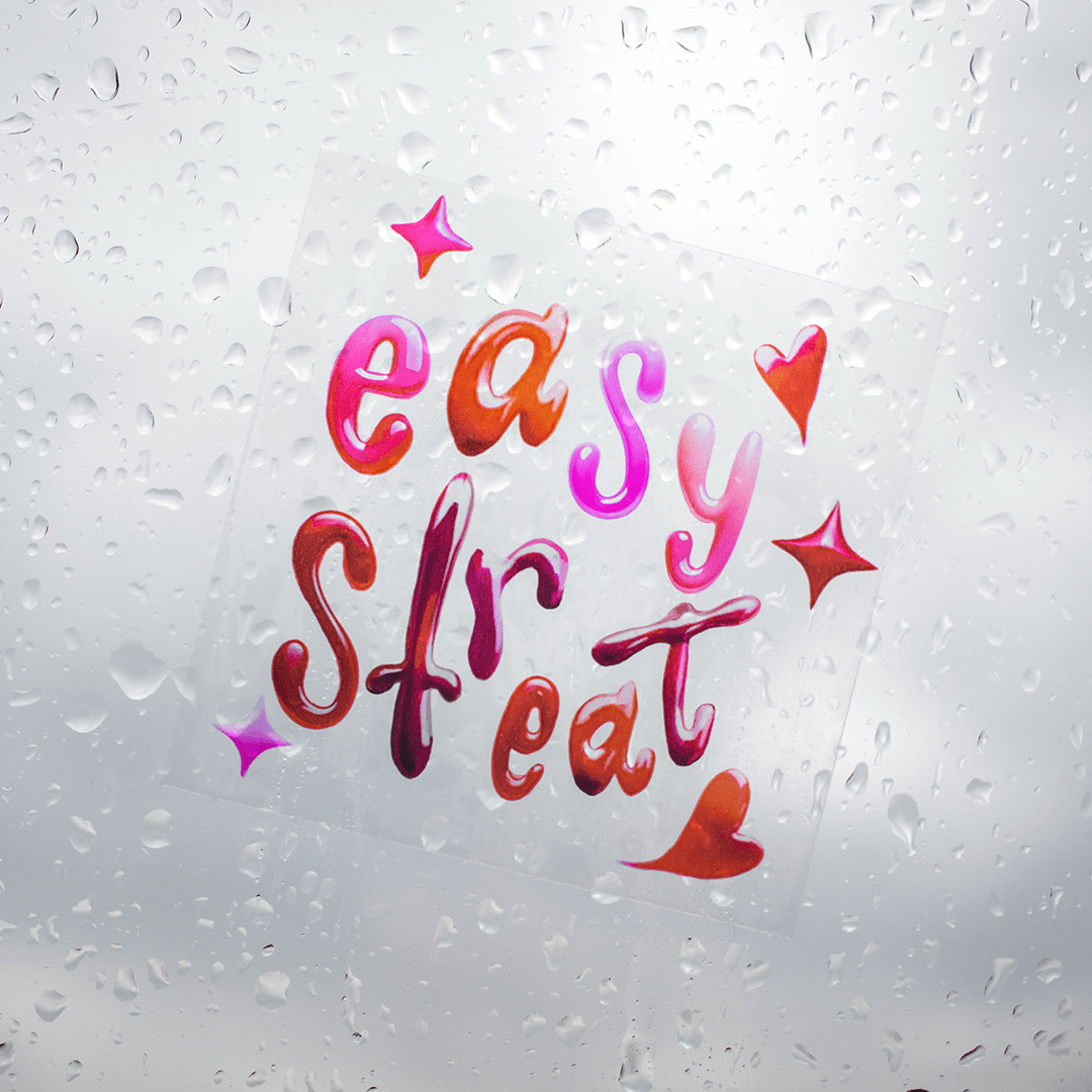 Transparent vinyl sticker with colorful Easy Street lettering design applied to glass with water droplets, showing clear background effect