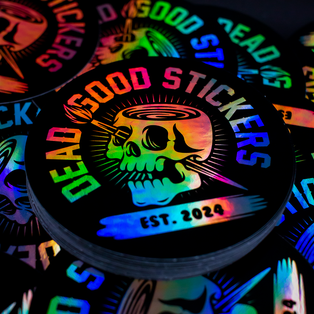 a circle holographic sticker with the deadgood stickers logo